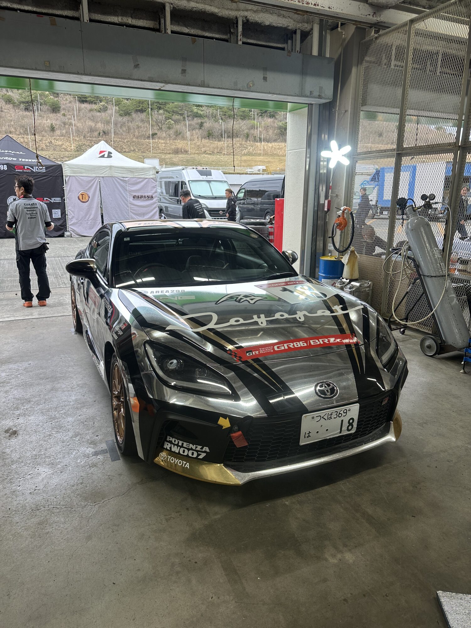サーキットのピットで車両を支えるメカニックチーム